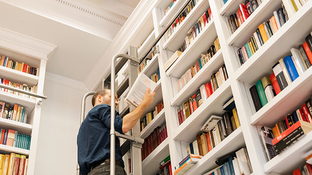 GHI Fellow Mario Peters retrieving a book from the library on a ladder